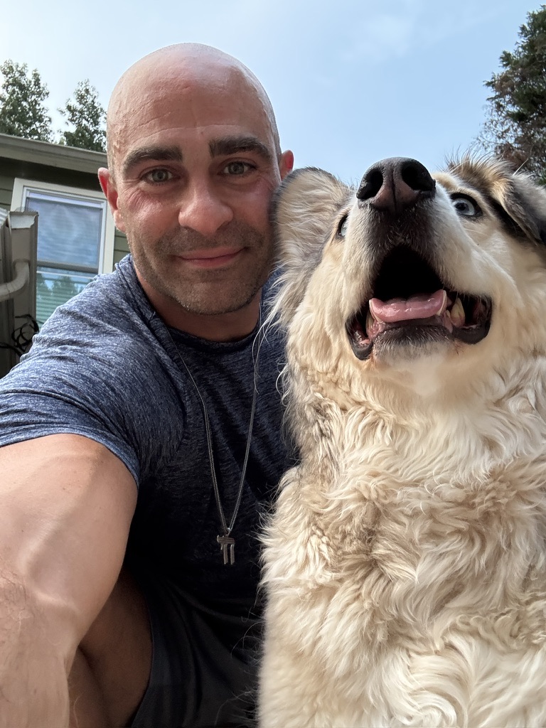 Isaac Dakar smiling outdoors with his dog, Beanie